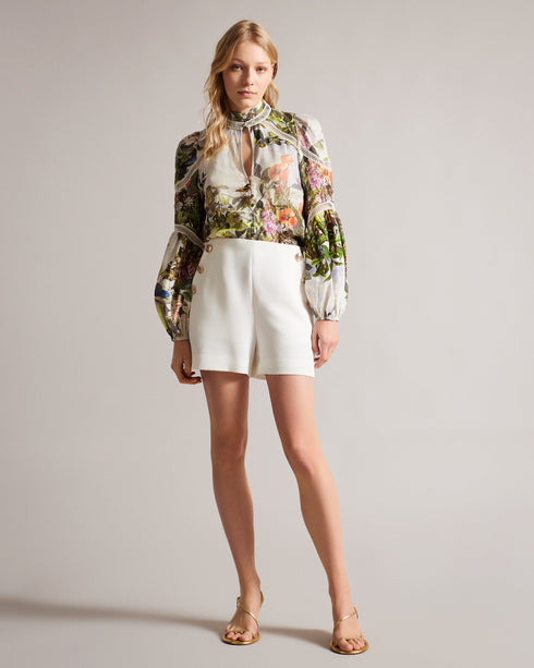 LUUCIAA-Tops-Introducing your new go-to blouse, LUUCIAA. Featuring our botanical scene print and elegant ladder lace inserts, this blouse has everything you need to make a statement. Keep it loose for a laidback attitude or tuck it into your trousers for a sleek style.This product is made with European Flax. It is farmed using no irrigation and no pesticides, helping to reduce water and chemical usage. Long sleeved blouse Botanical scene print Ladder lace inserts 100% linen Stand collar with keyhole cut-out